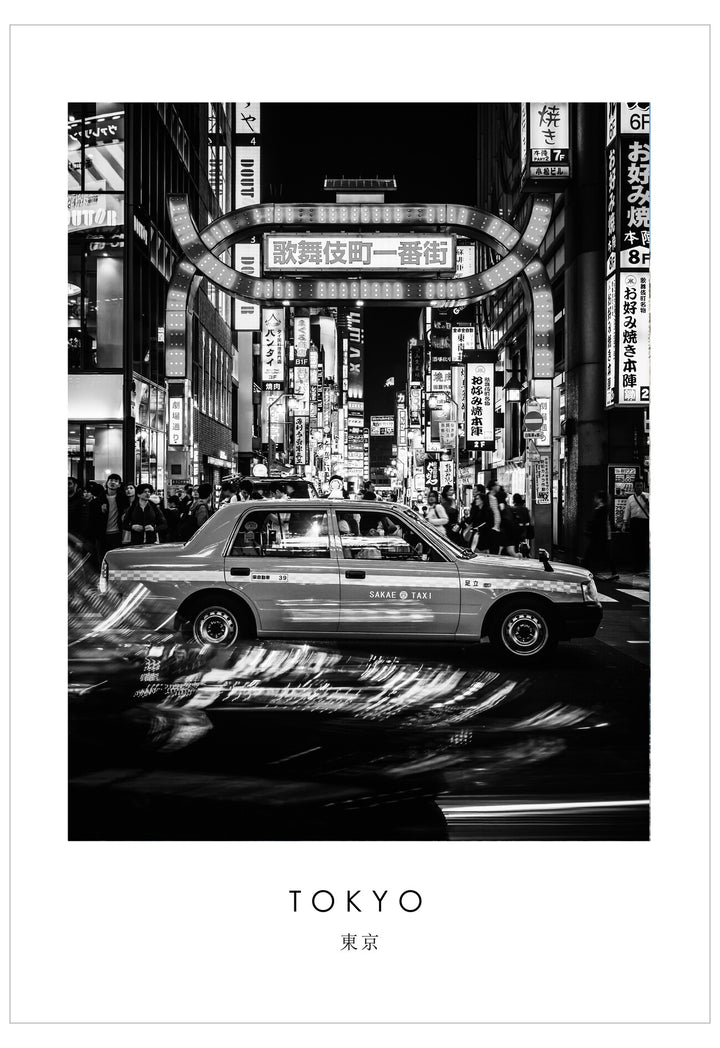 Black and white image of a taxi in a bustling Tokyo street at night.