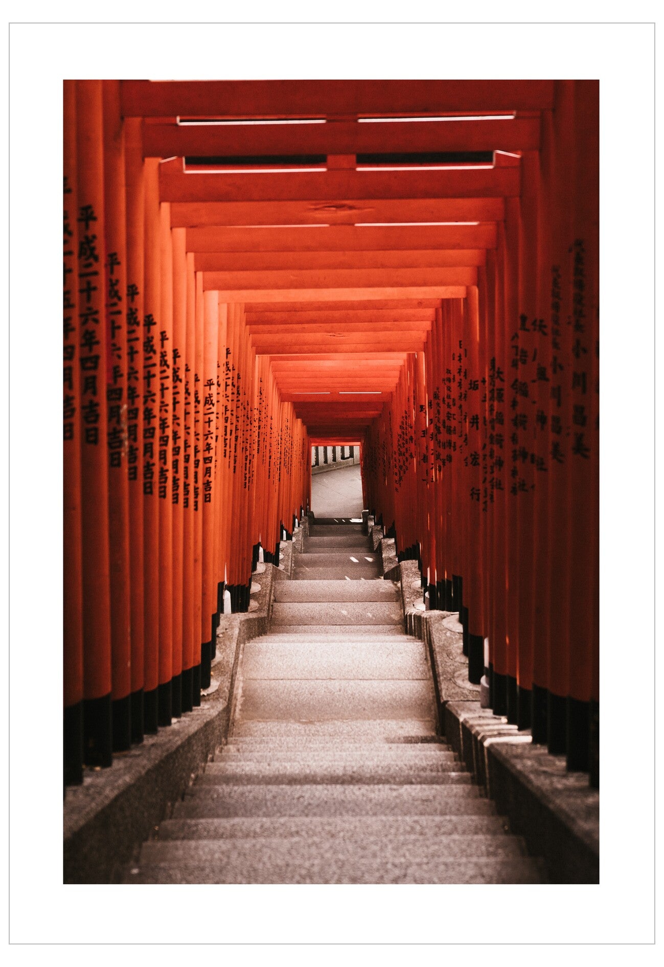 Long corridor of red torii gates with stone steps leading into the distance.