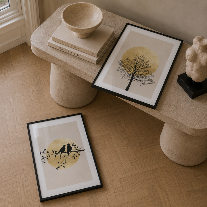 Decorative setup with framed artwork, books, and a sculpture on a wooden floor.