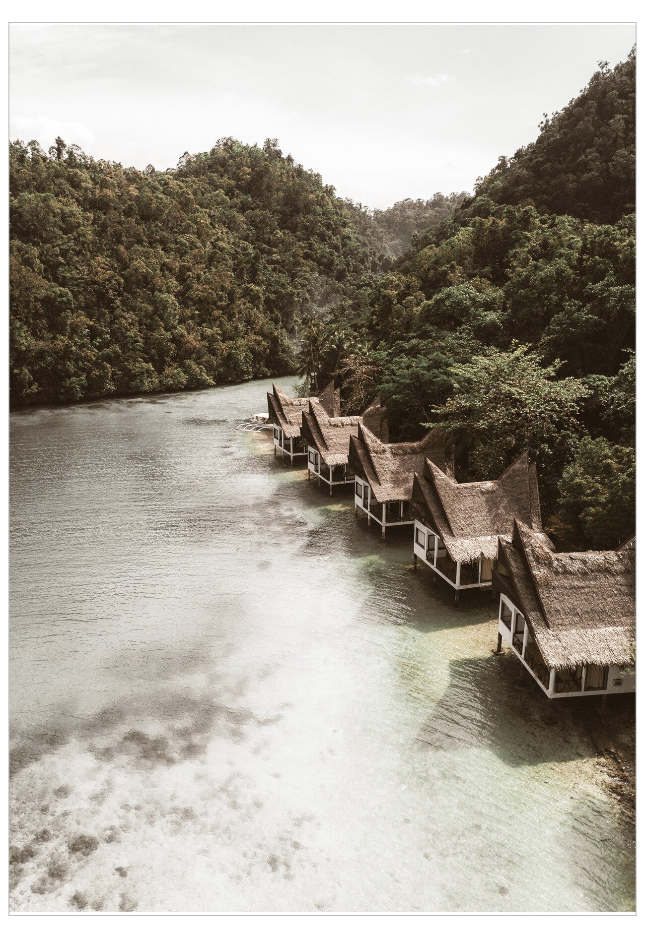 Thatched roof huts along a river surrounded by lush greenery