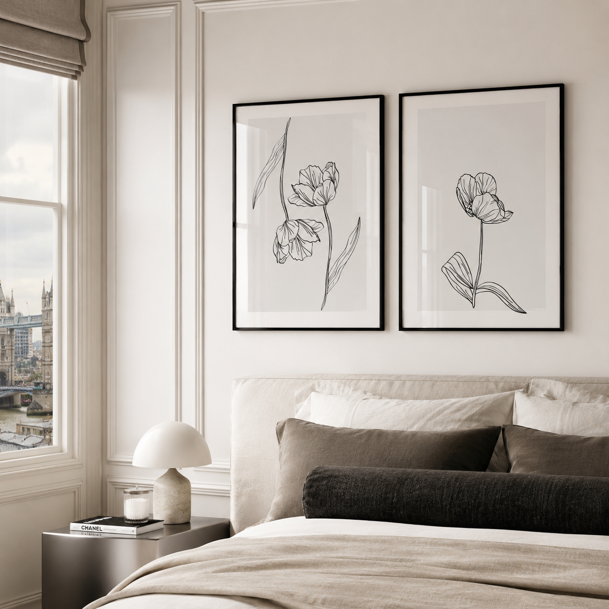 Two framed black and white botanical line art prints hanging side-by-side on a cream wall above a bed with neutral-toned bedding in a modern bedroom setting.