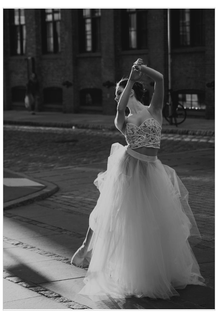 Dancer in a white outfit performing outdoors with a building in the background