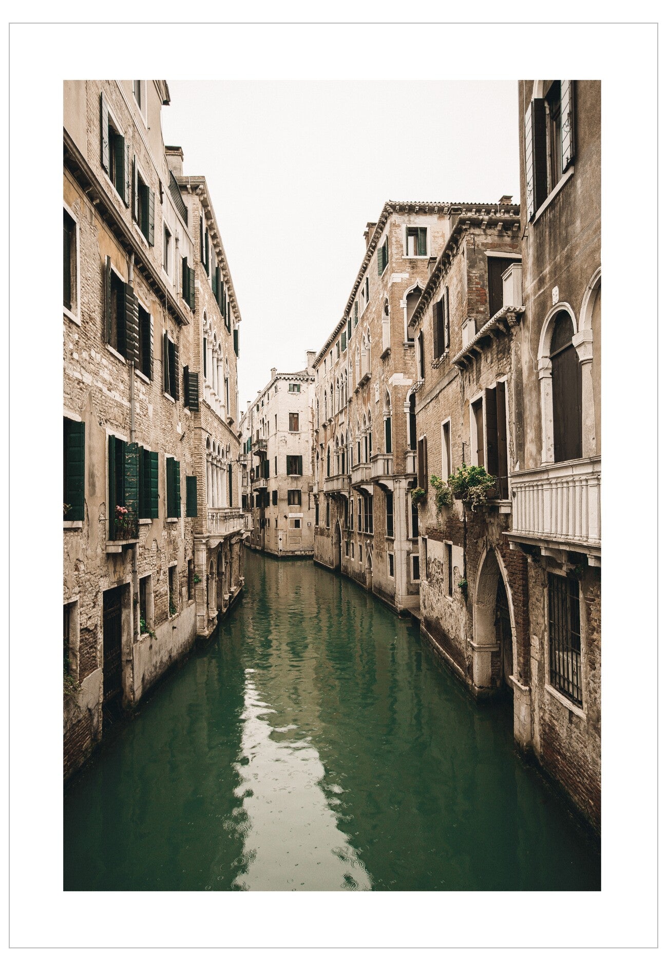  narrow canal flanked by tall, old stone buildings in Venice