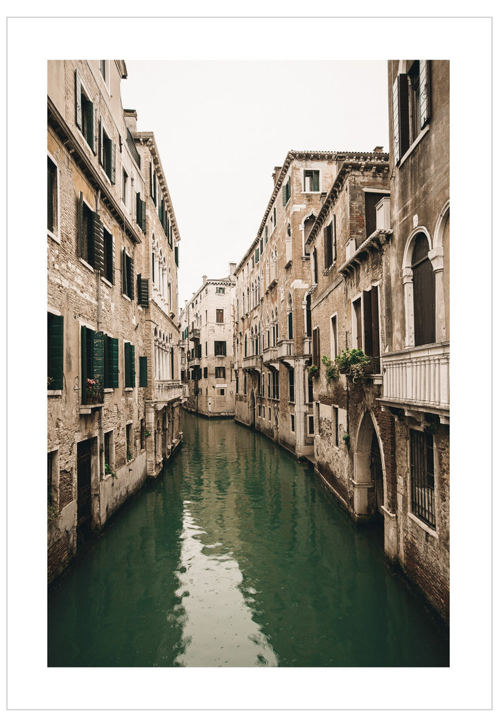  narrow canal flanked by tall, old stone buildings in Venice