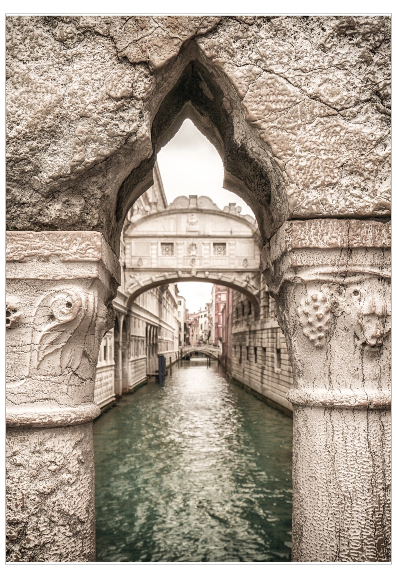 Stone archway over a canal with buildings in the background