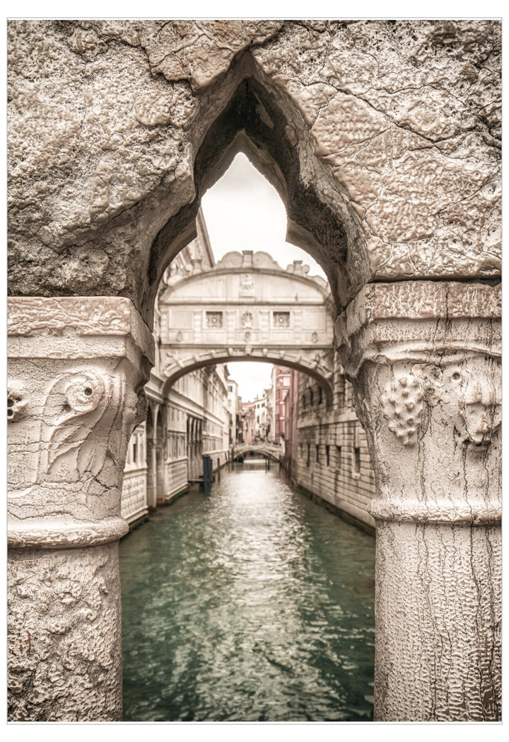 Stone archway over a canal with buildings in the background