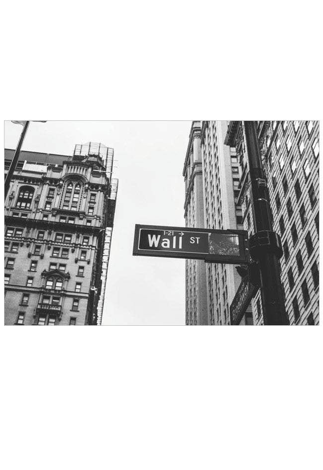 Black and white street sign for Wall St with tall buildings in the background