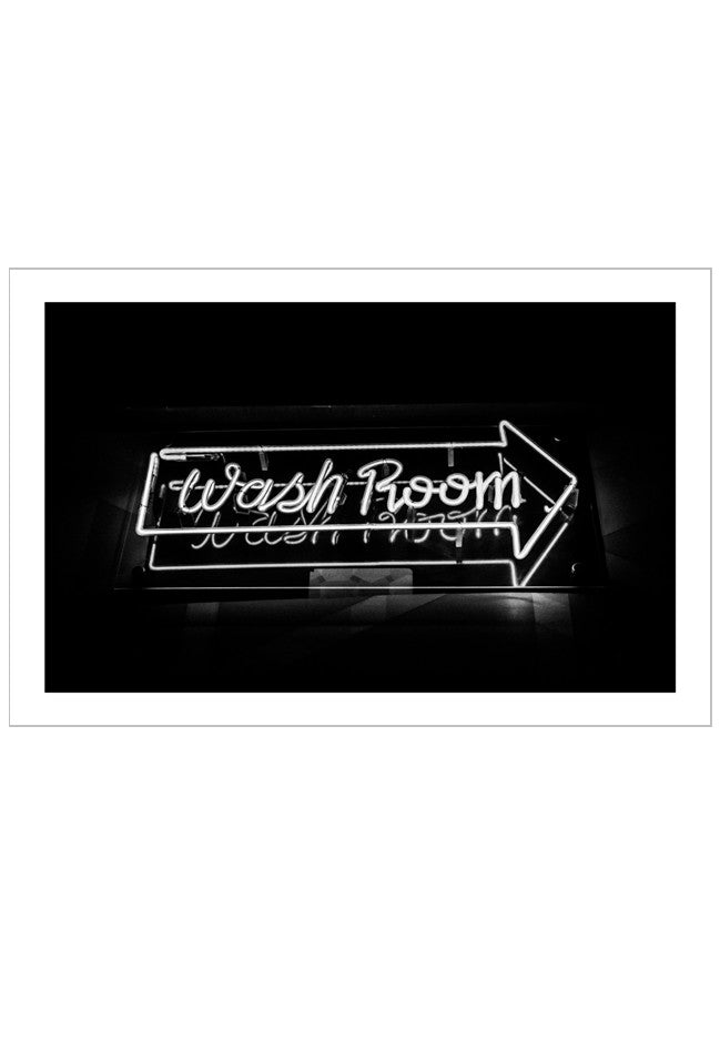 Neon sign pointing to a washroom with text on a black background