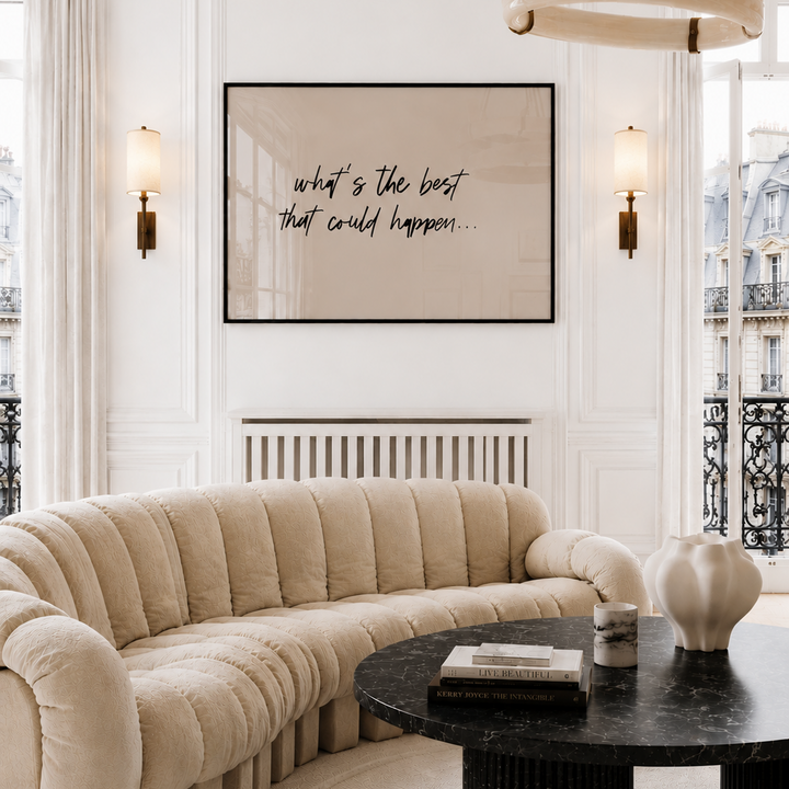Modern living room with beige sofa, black coffee table, and framed quote on wall.