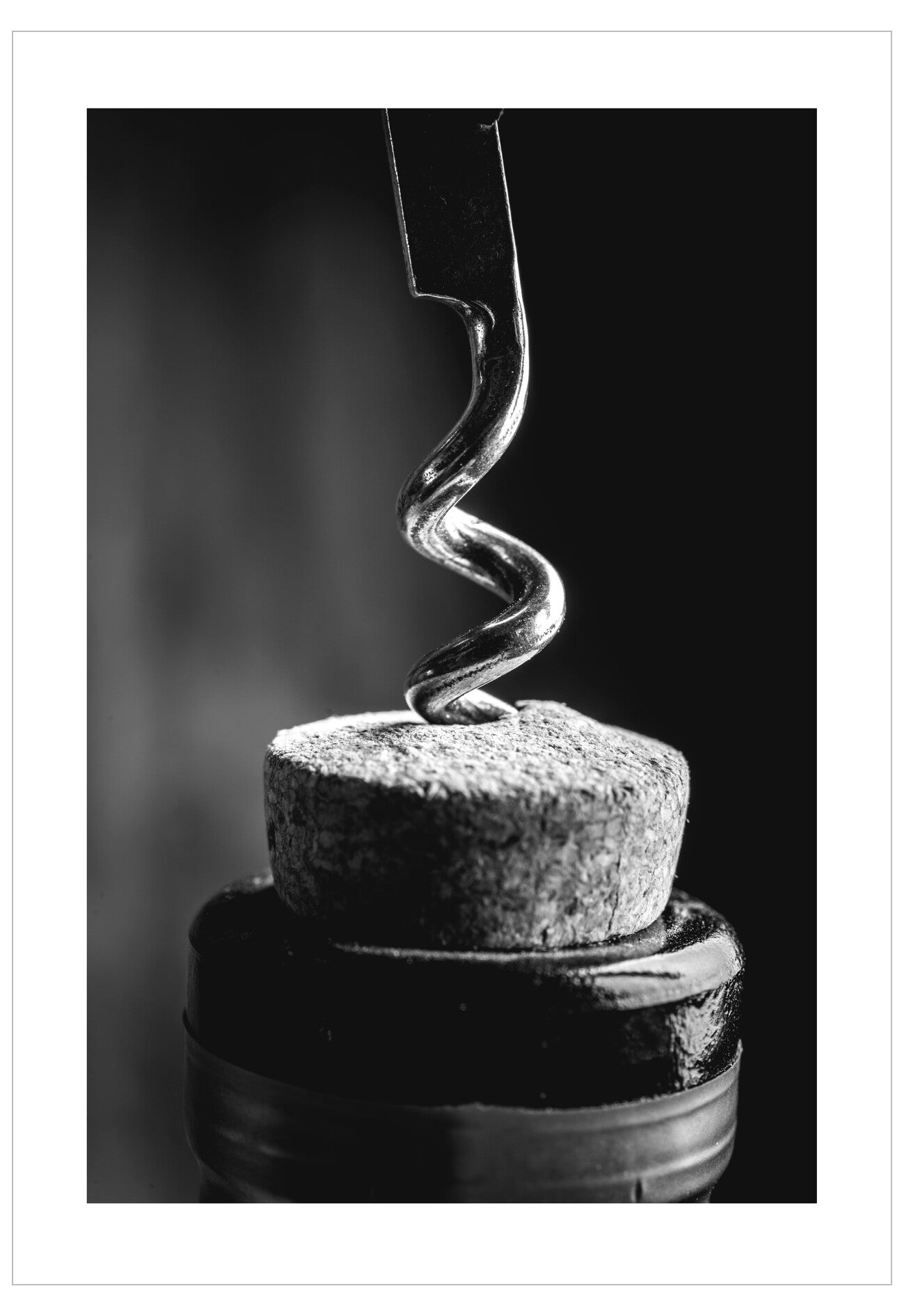 Corkscrew inserted into a cork on a dark background