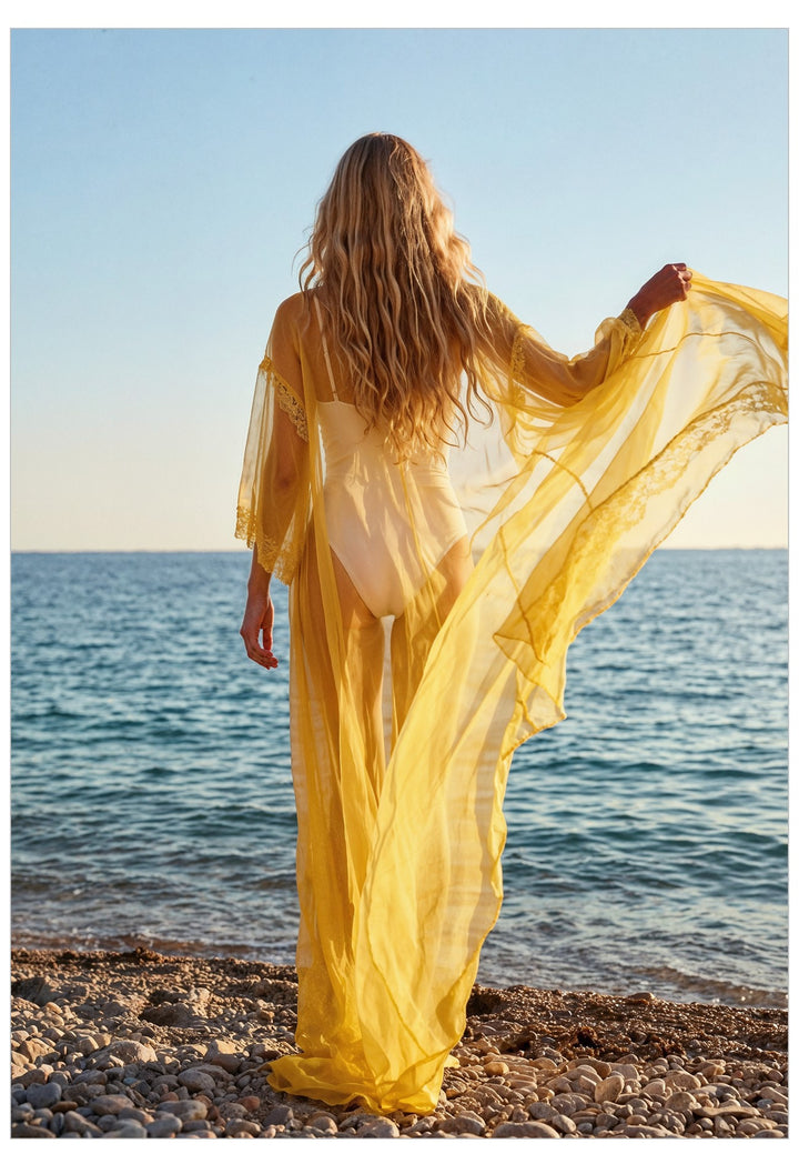 Woman in a yellow dress standing on a beach with ocean view