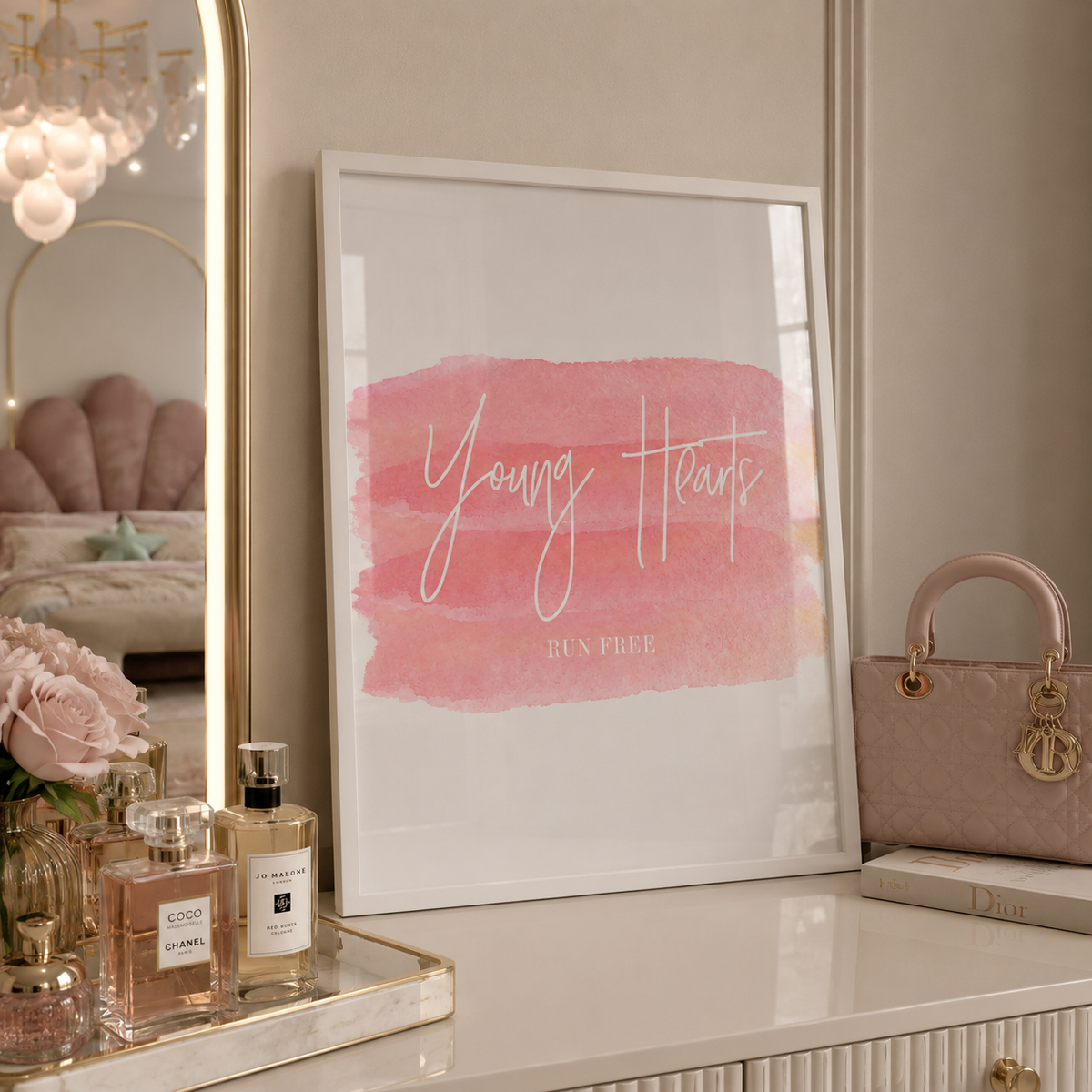 Decorative setup with a framed print, perfume bottles, and a handbag on a surface.