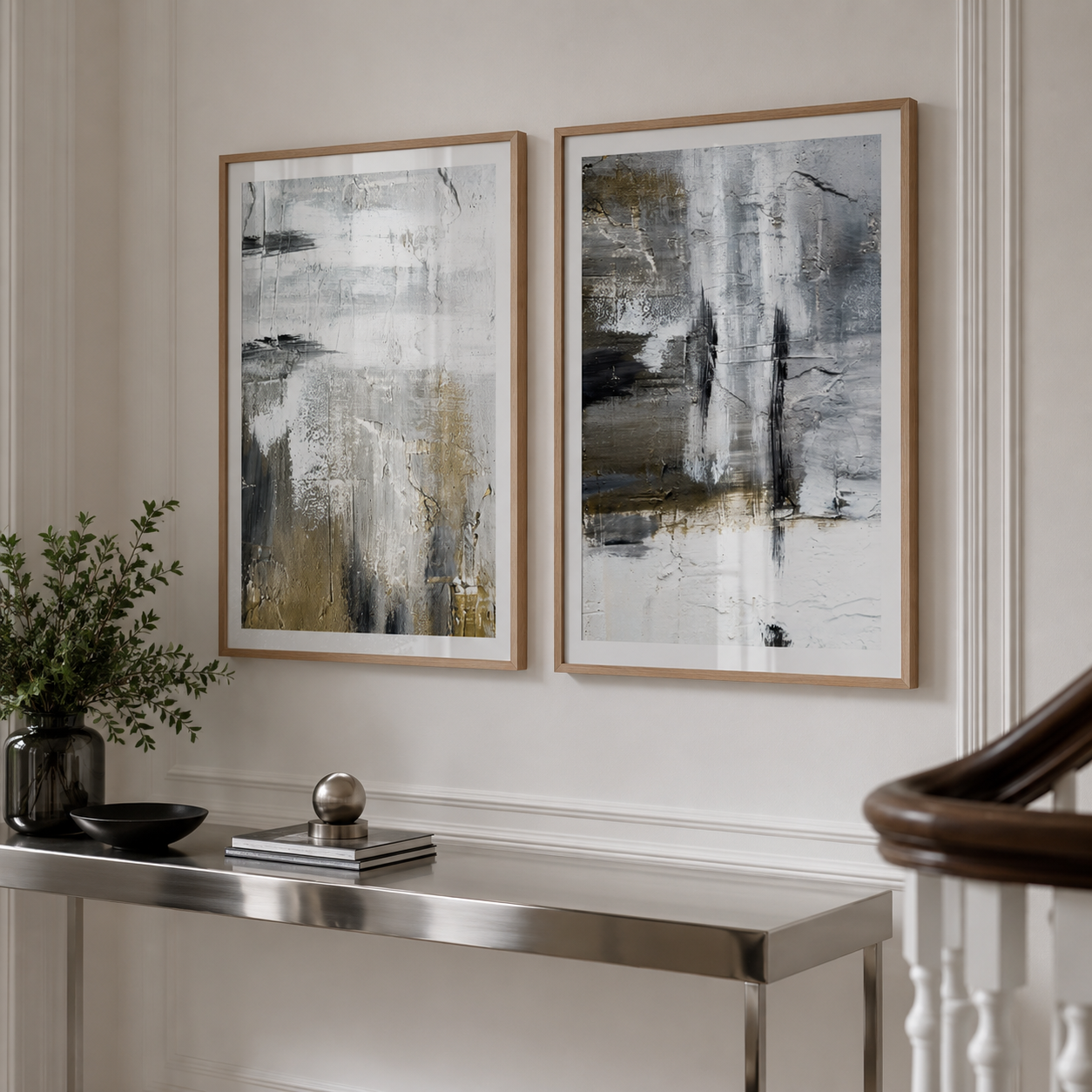 Two framed abstract wall art prints hang side by side on a light neutral wall above a console table in a styled interior setting.