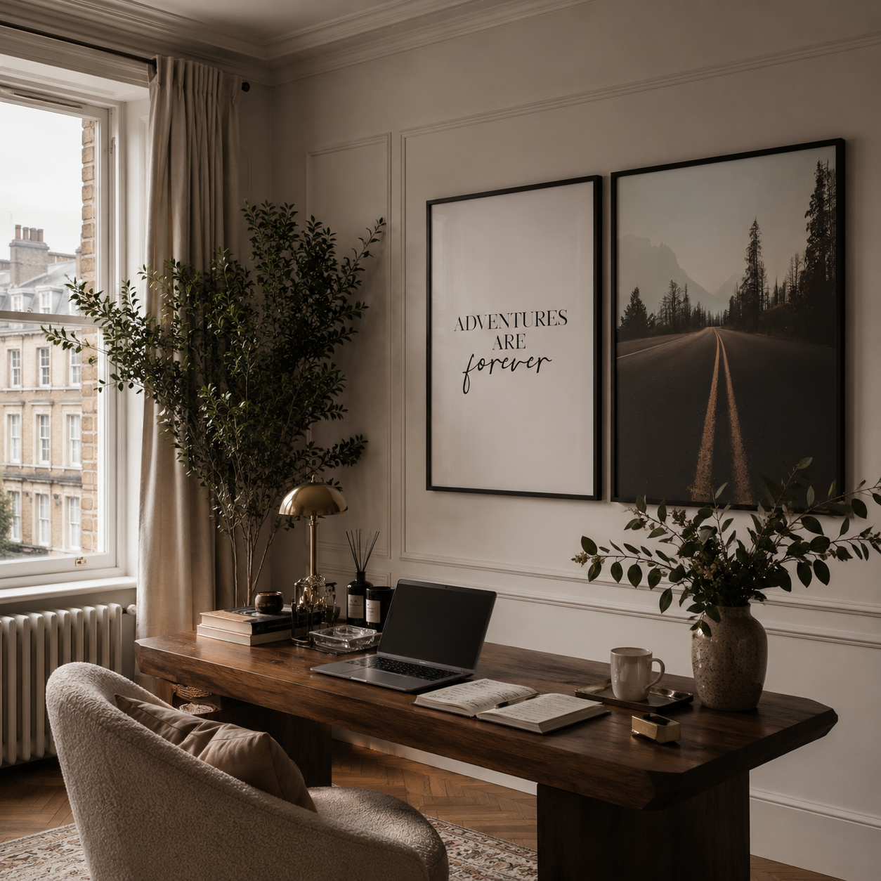 A styled home office interior with a dark wood desk, beige armchair, potted plants, and two framed wall art prints hanging on a cream paneled wall. One print reads “ADVENTURES ARE forever.