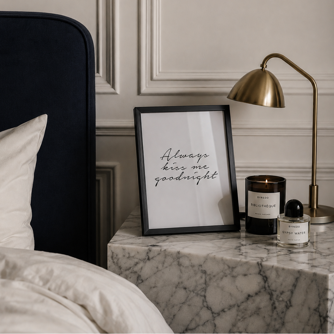Nightstand with framed quote, lamp, and candles in a bedroom setting