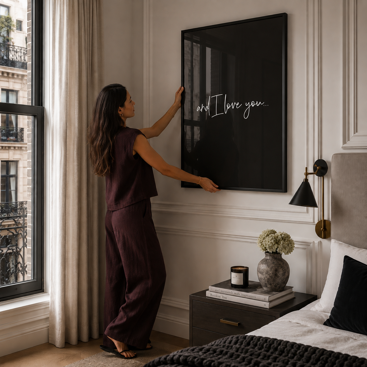 Woman adjusting a framed picture in a bedroom.