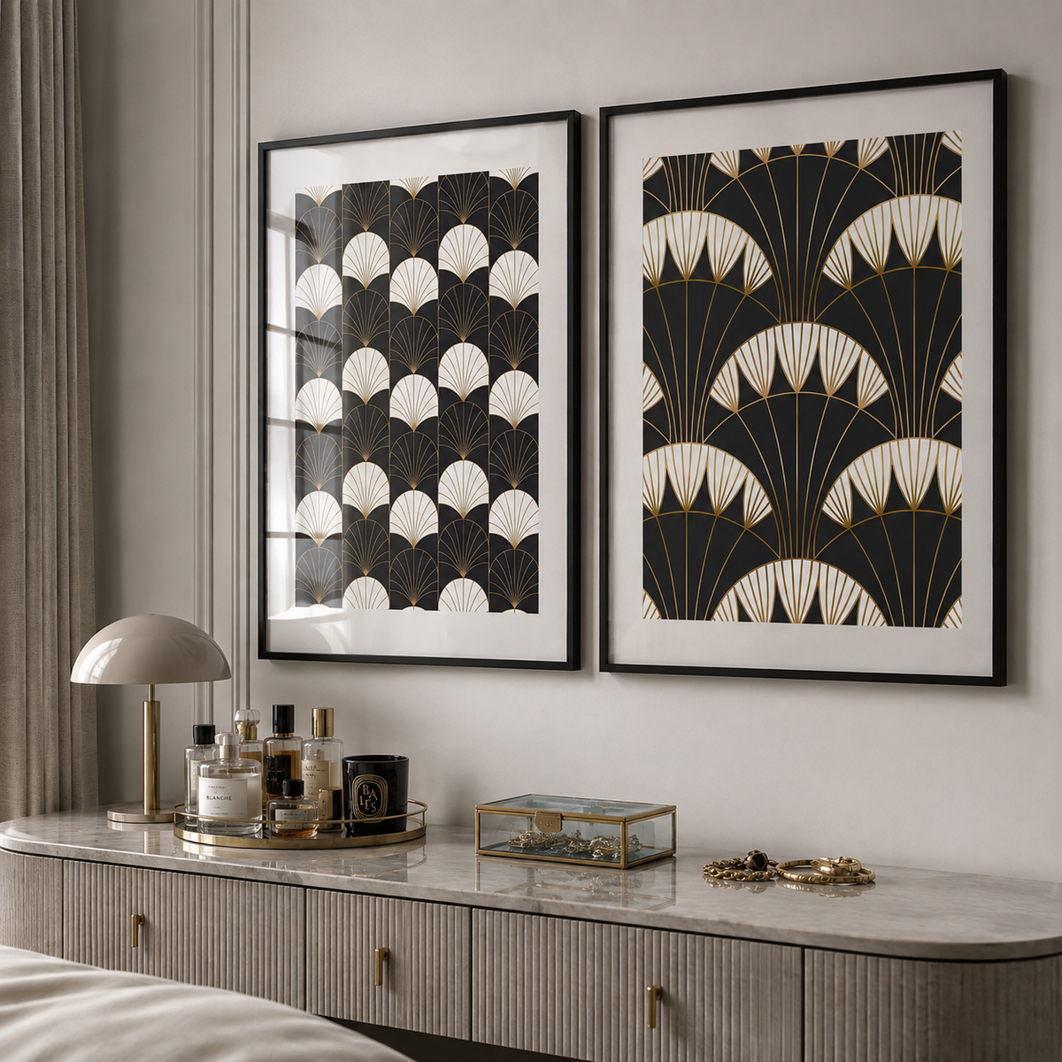 Two framed Art Deco style wall art prints with black, white, and gold fan patterns, displayed side-by-side on a light gray wall above a marble console table with decorative items.