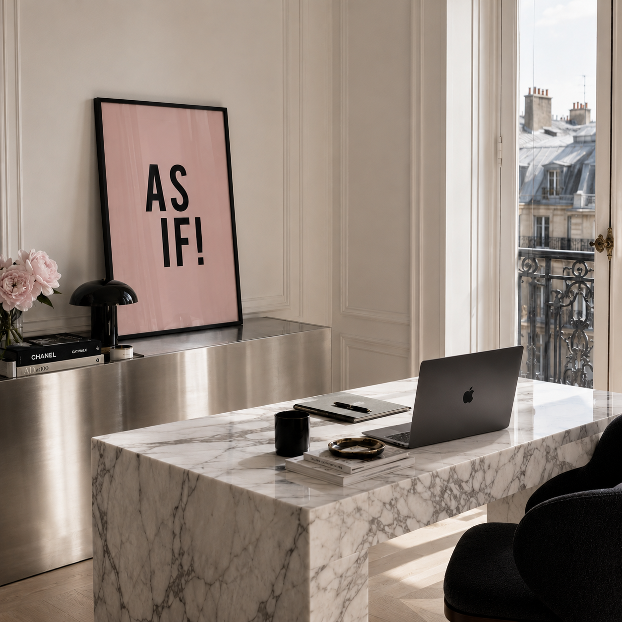 A styled interior scene with a large framed pink wall art print inspired by the 90's movie 'CLUELESS' reading 'AS IF!' leaning on a metallic console table. In front is a marble desk with a laptop, mug, books, and accessories, with a window showing an urban balcony view in the background.