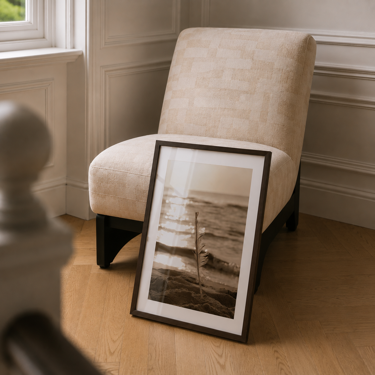 Framed photograph leaning against a beige armchair on a wooden floor.