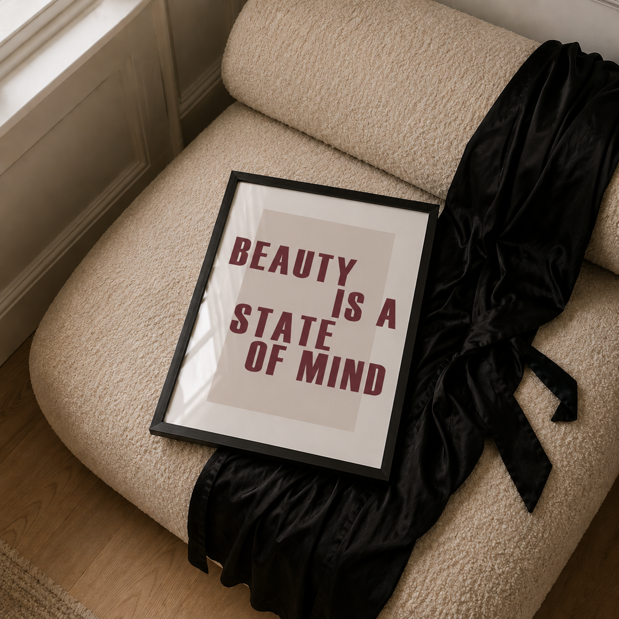Framed quote 'Beauty is a State of Mind' on a textured surface with a black garment.