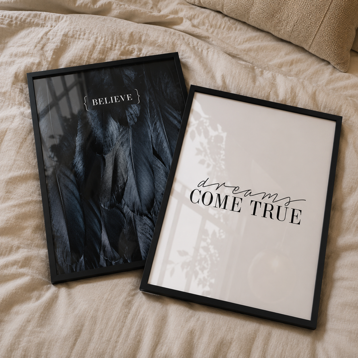 Two framed prints on a bed, one with 'BELIEVE' and the other with 'dreams COME TRUE'.