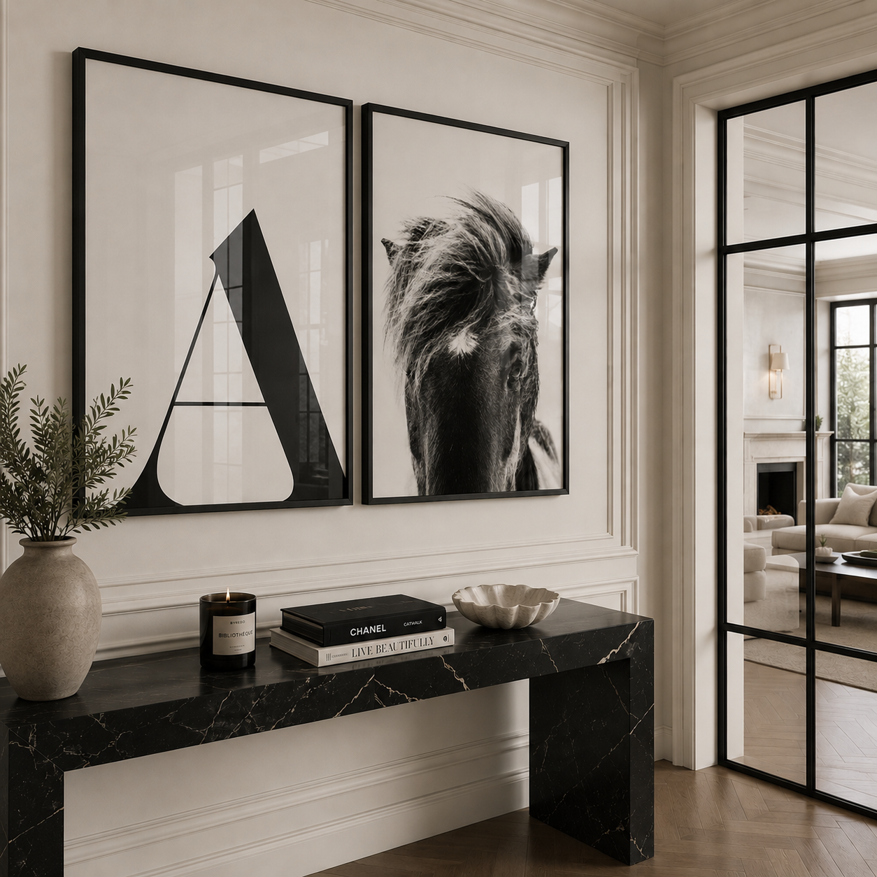 Two large black-framed wall art prints hang above a black marble console table in a bright, modern room. The left print features a bold black geometric letter A on a white background, and the right print shows a black-and-white close-up of a horse's mane.