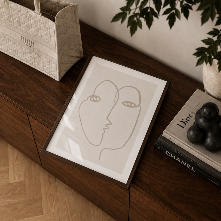 Framed abstract art print on a wooden surface with Dior and Chanel items.