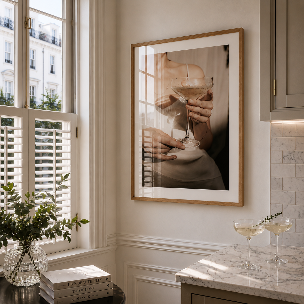 Framed artwork of a person holding a cocktail in a stylish room with a window and books.