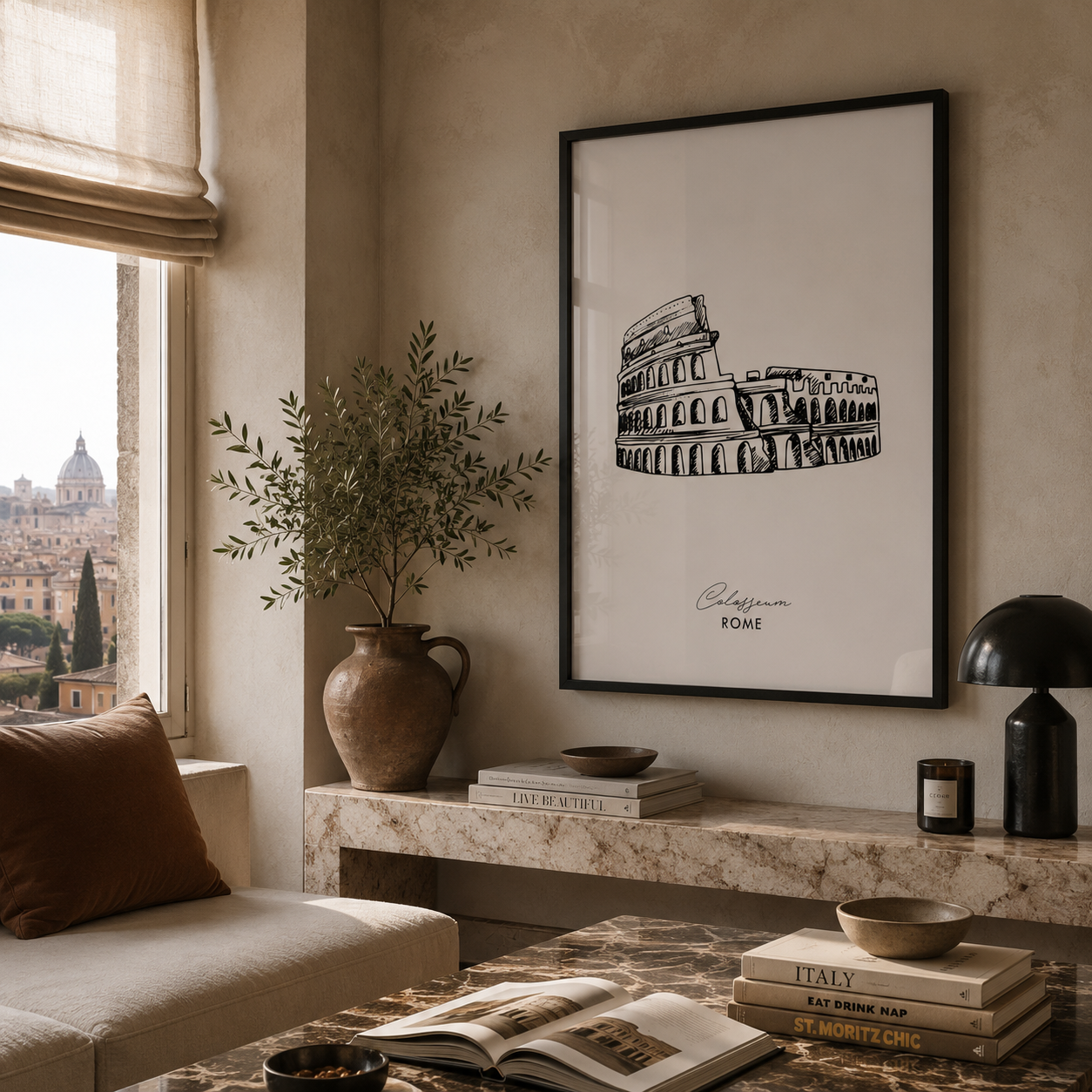 A framed black-and-white architectural art print of the Colosseum in Rome hangs on a beige wall in a styled living room setting with a marble console table, books, a lamp, and a window view.