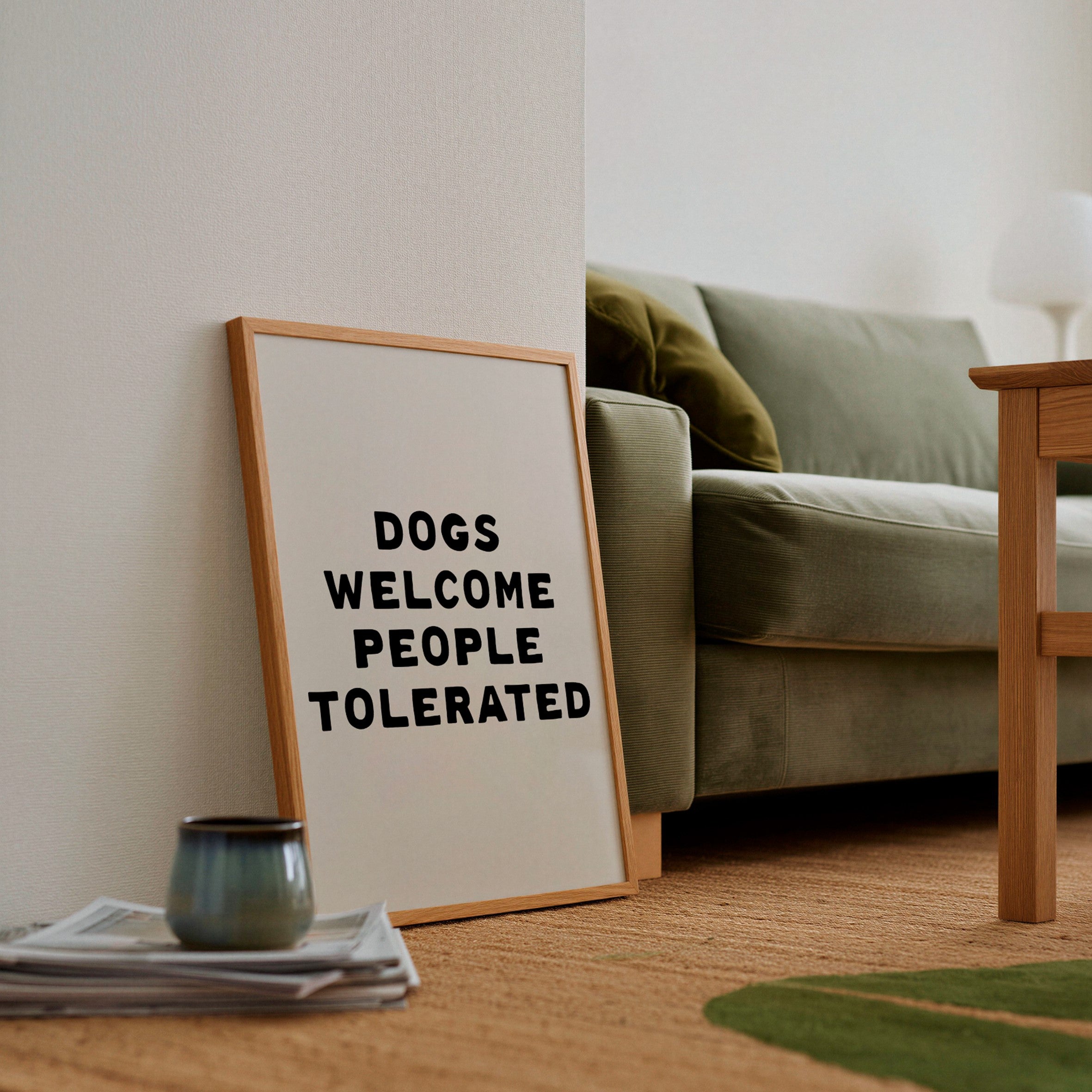 Framed sign with 'Dogs Welcome, People Tolerated' text in a living room setting.