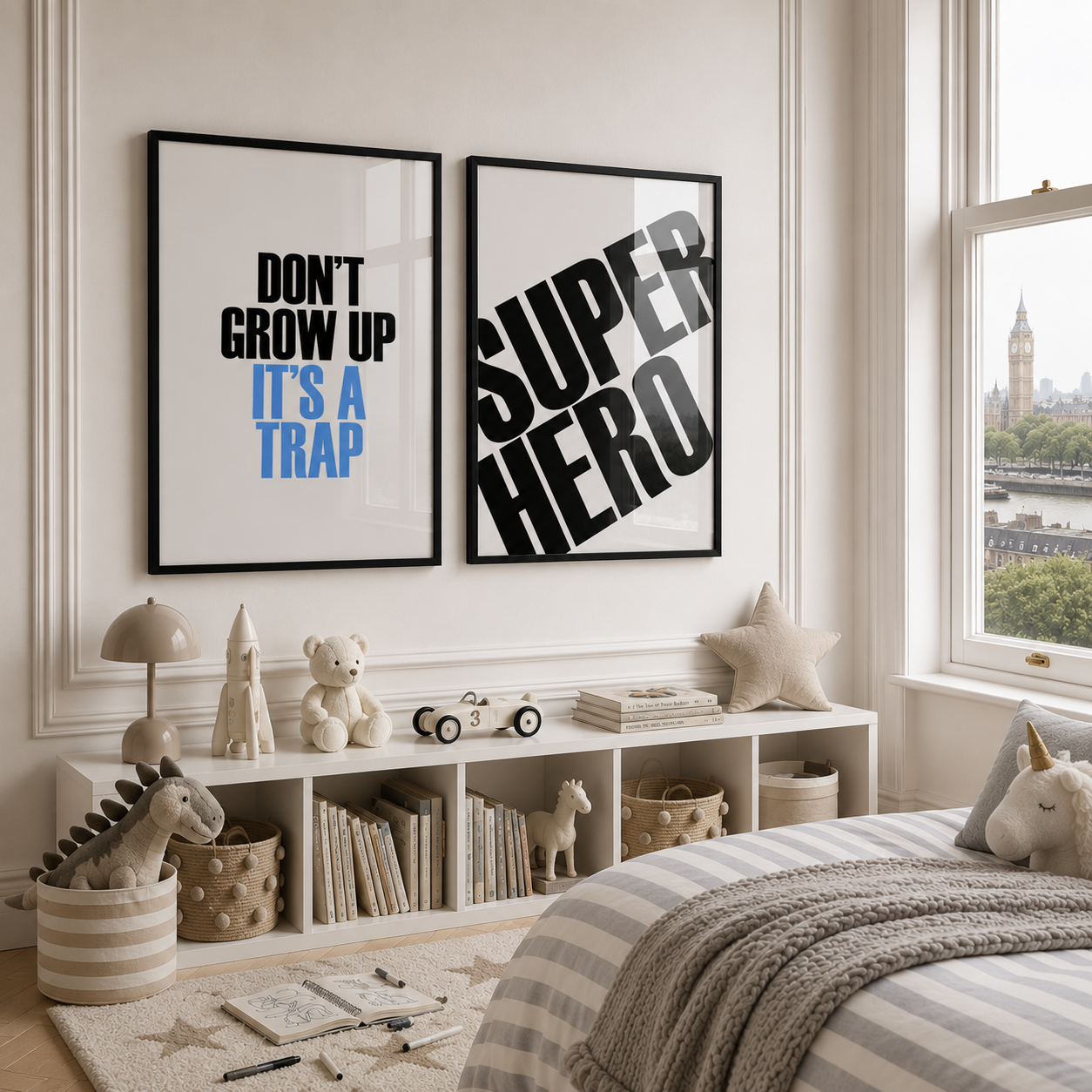 Two framed wall art prints displayed above a white shelf in a styled children's bedroom. The left print reads 'DON'T GROW UP IT'S A TRAP' in black and blue text, and the right print reads 'SUPER HERO' in large black letters.