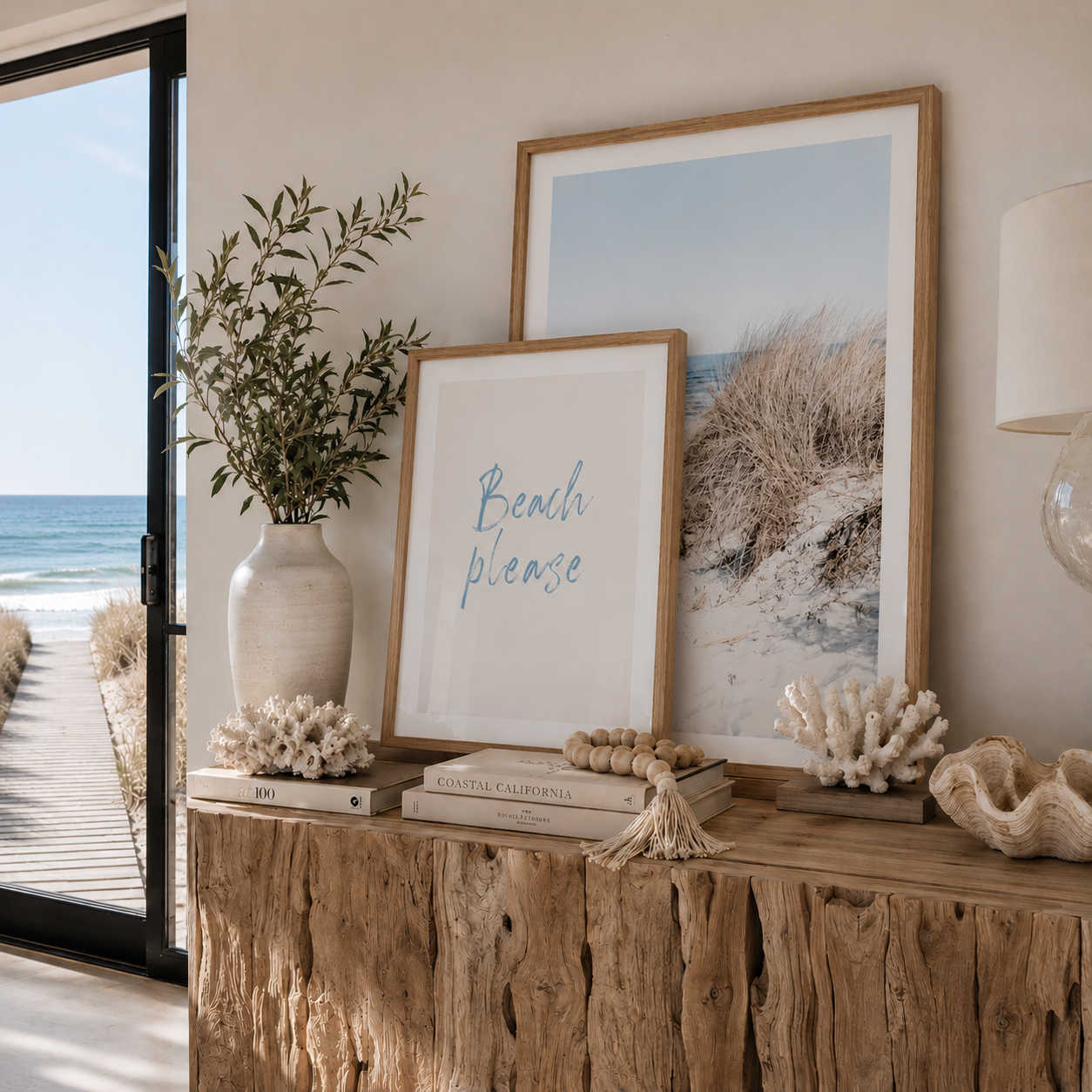 Decorative console table with beach-themed decor including framed pictures and a vase.