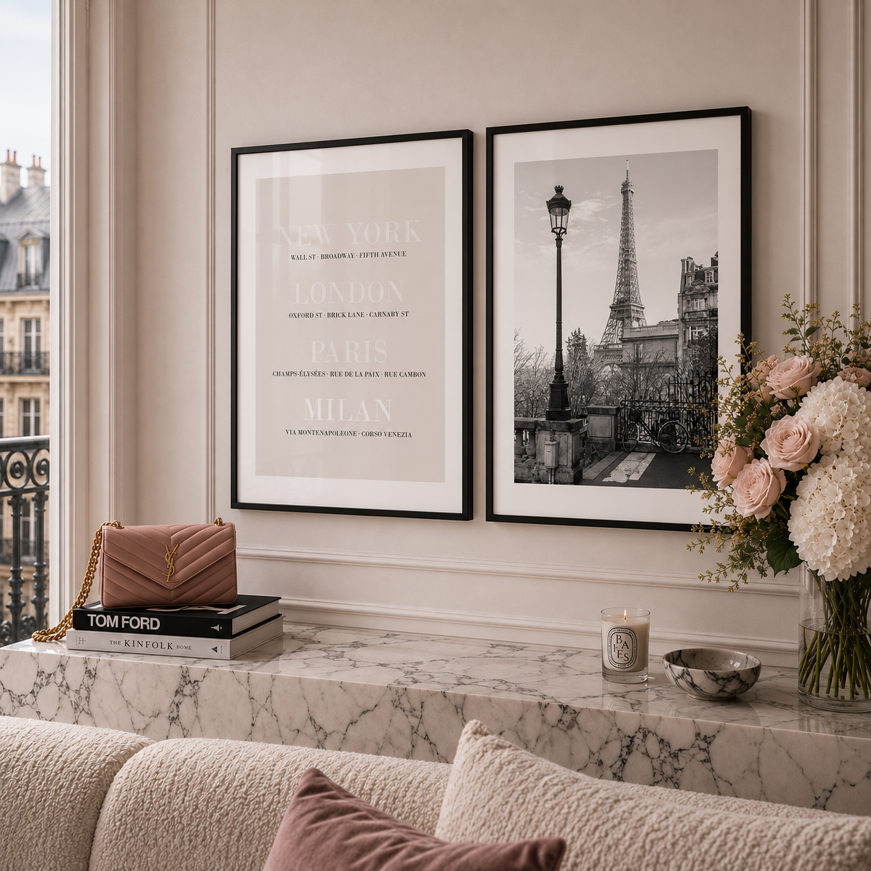 Two framed wall art prints hang above a marble console table in a styled interior. The left print is a minimalist city names poster, and the right print is a black-and-white Paris scene with the Eiffel Tower.