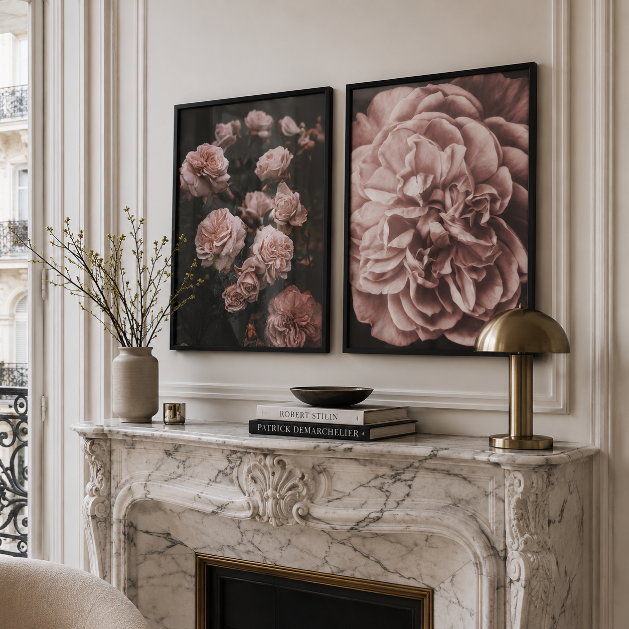 Two framed floral wall art prints hang above a marble fireplace mantel in a styled interior. The left print shows pink roses on a dark background, and the right print shows a large pale pink flower.