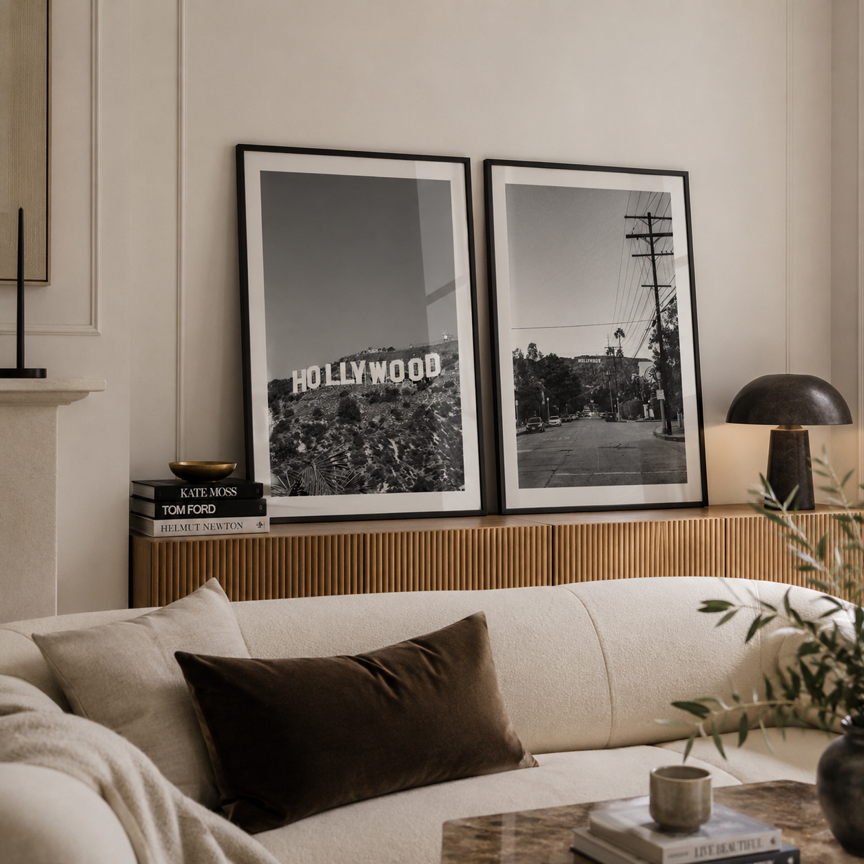 Two framed black and white art prints of the Hollywood sign and a street scene, displayed on a wooden console above a cream sofa in a modern living room setting.