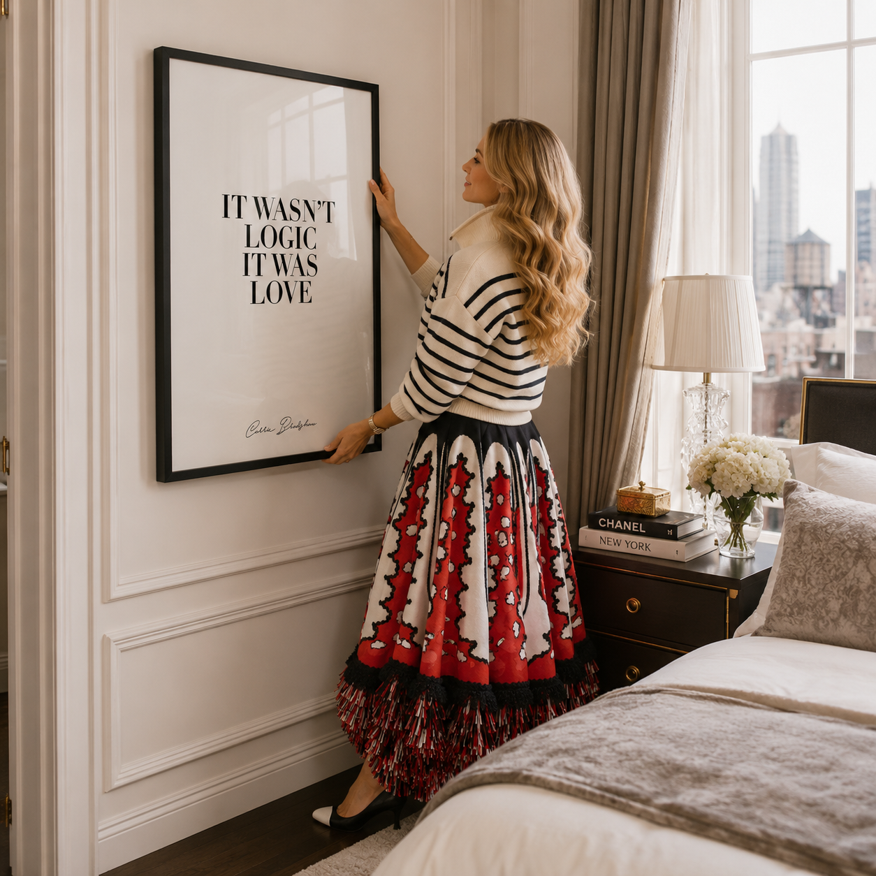 A woman in a bedroom adjusts a large black-framed wall art print featuring the quote 'IT WASN'T LOGIC. IT WAS LOVE.