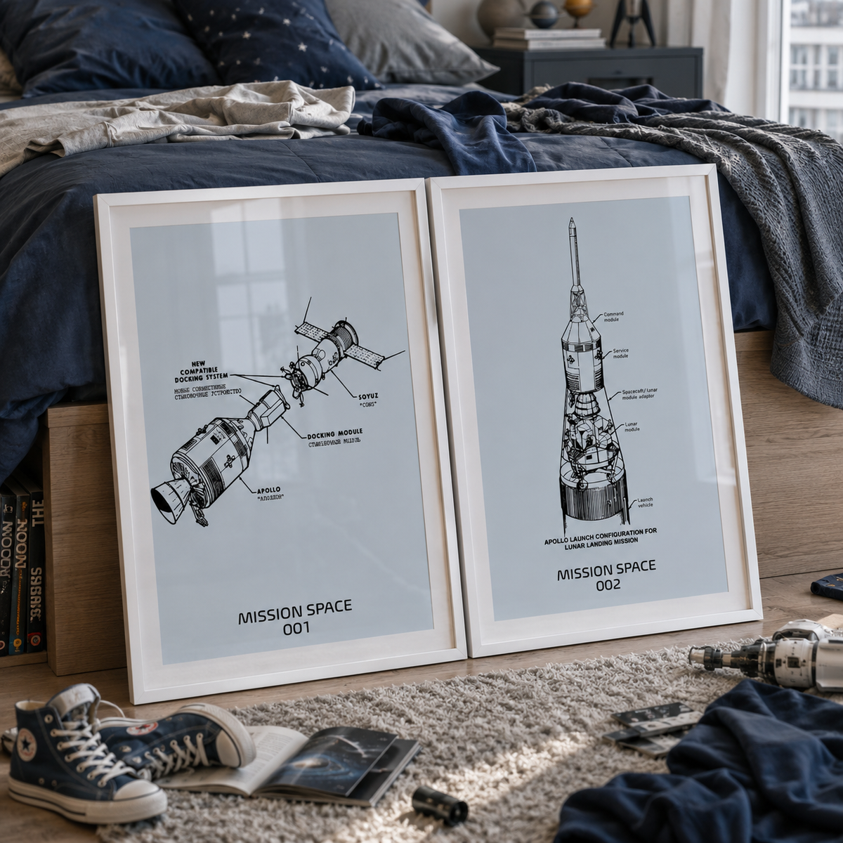 Two framed black-and-white space-themed technical prints leaning against a bed in a styled bedroom. The prints show labeled rocket and spacecraft schematics with the text 'MISSION SPACE 001' and 'MISSION SPACE 002'.