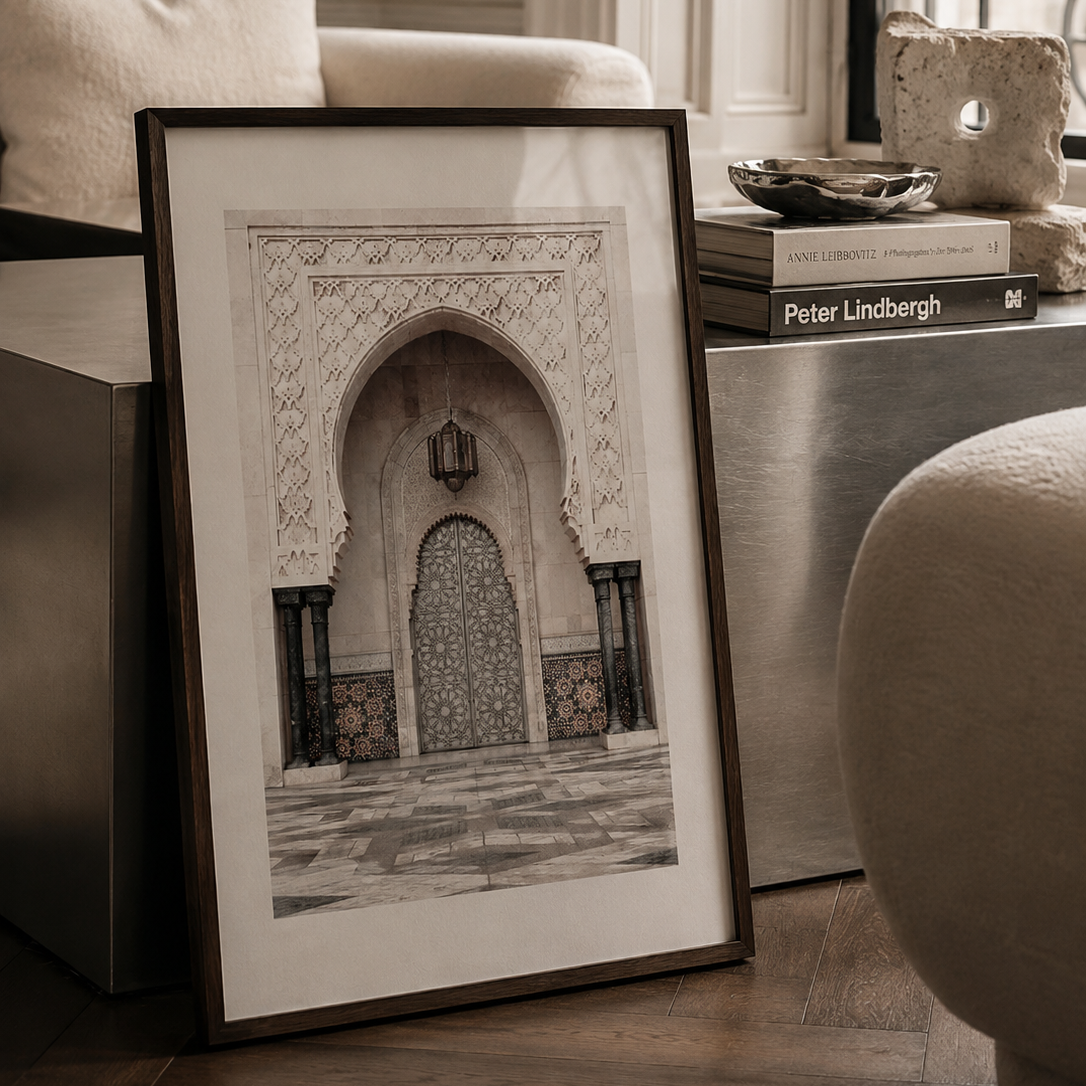 A framed art print featuring a detailed architectural illustration of an Islamic archway, styled in a modern living room setting next to a sofa and side table.