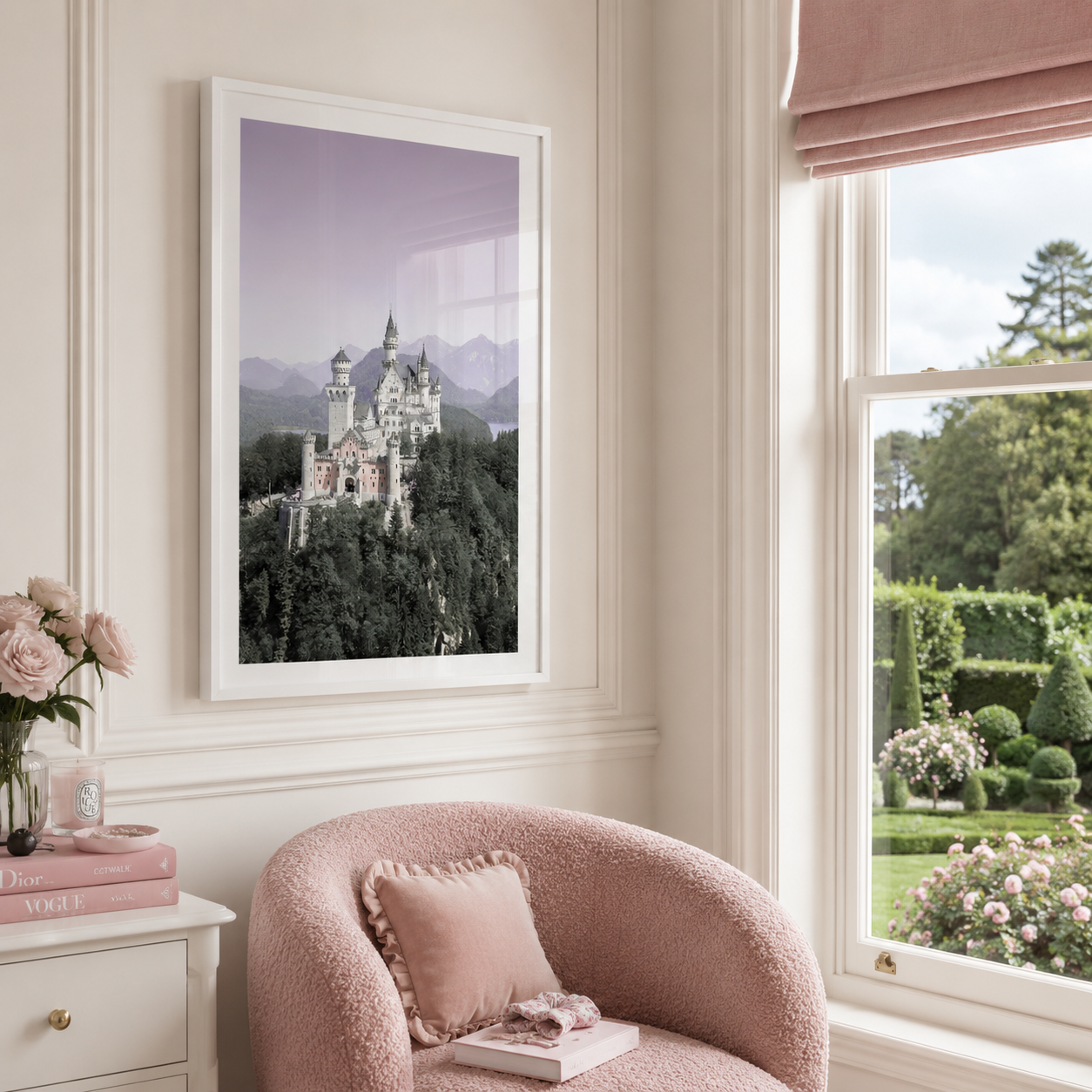 A framed art print depicting a fairytale castle on a hill under a lavender sky, styled in a bright, modern room above a pink armchair next to a window.