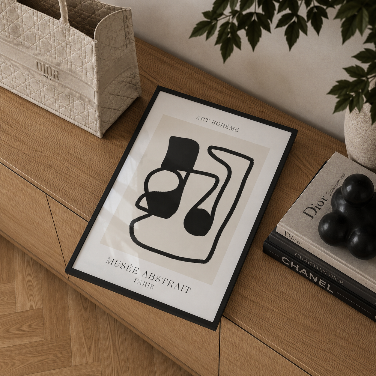 Framed abstract art print on a wooden surface with books and a Dior bag.