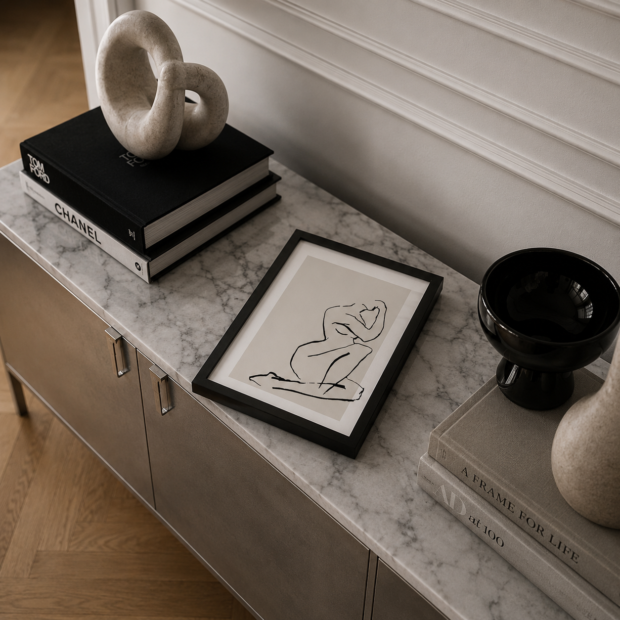 Framed artwork on a marble surface with books and decorative items.