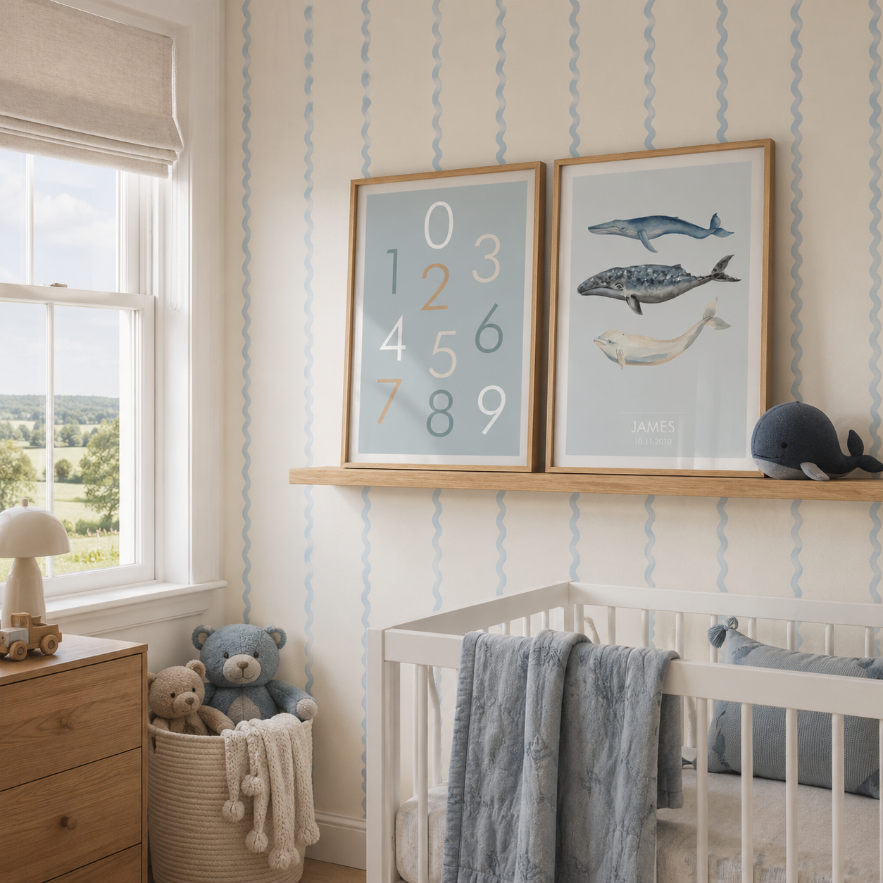 A styled nursery room featuring two framed art prints hanging on a wall above a wooden shelf and white crib. The prints include a pastel number chart and a whale illustration.