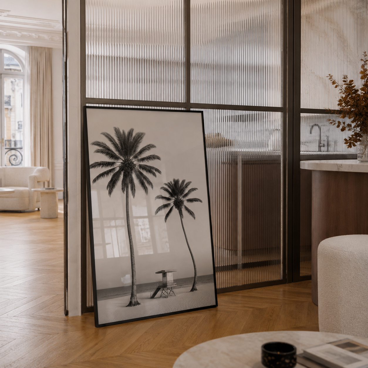 Framed black and white palm tree print leaning against a glass wall in a modern living room.