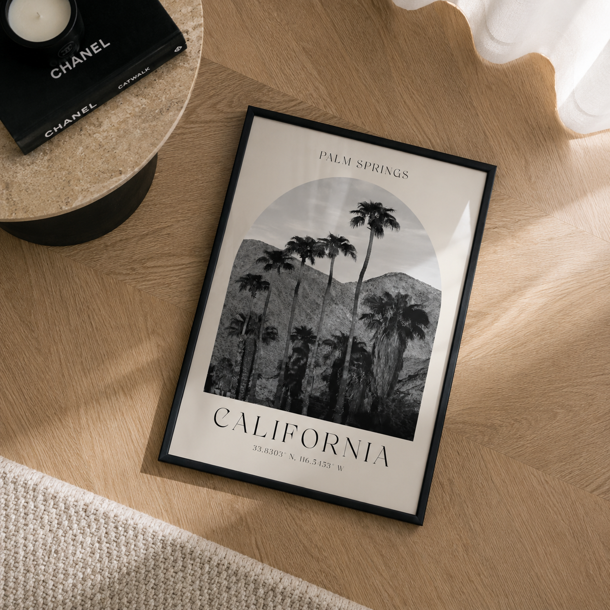 Framed print of palm trees and mountains with 'California' text on a wooden surface.
