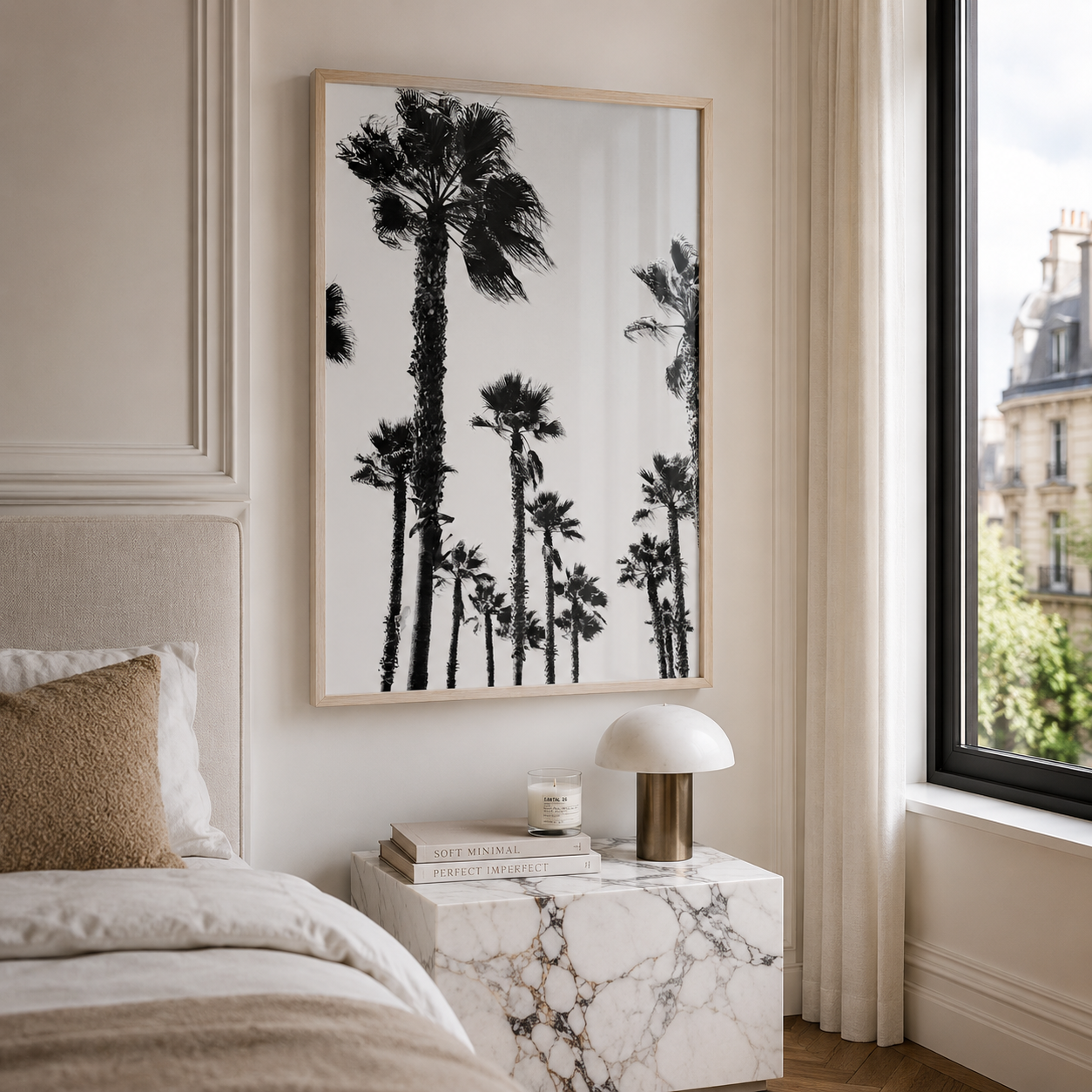 A framed black and white palm tree wall art print hangs above a marble nightstand in a styled bedroom setting.