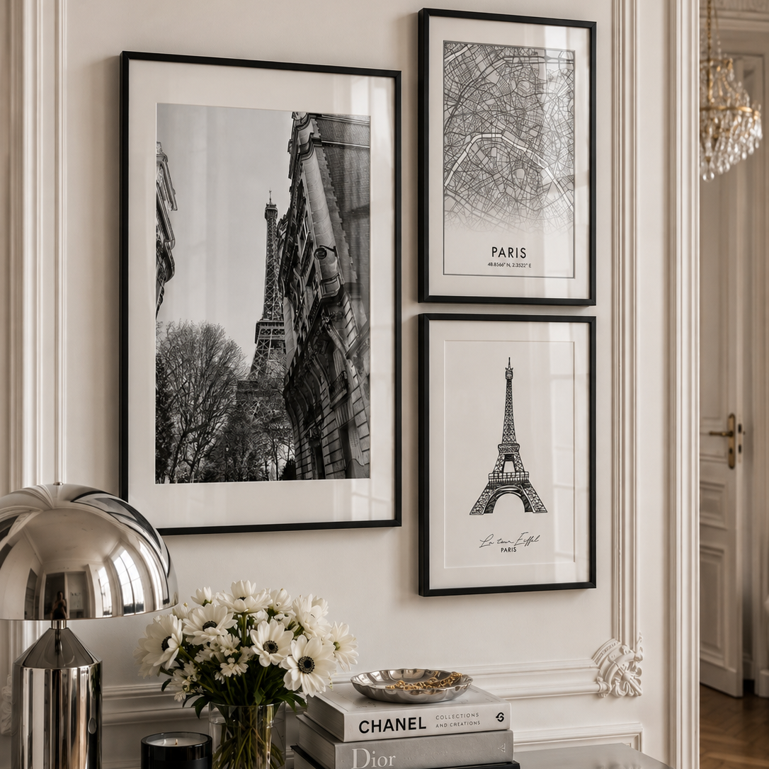 Three framed black and white Paris-themed art prints featuring the Eiffel Tower and architectural details, displayed on a cream wall above a console table with decorative items.