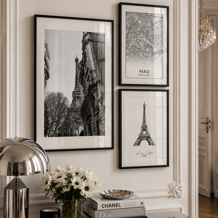 Three framed black and white Paris-themed art prints featuring the Eiffel Tower and architectural details, displayed on a cream wall above a console table with decorative items.
