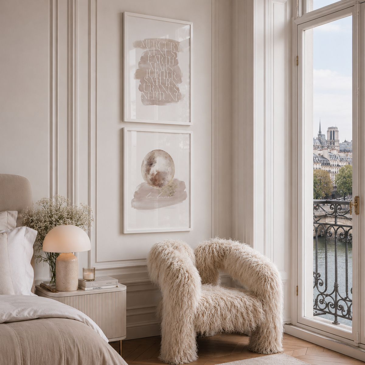 A styled bedroom corner with two framed abstract art prints hanging on a cream paneled wall above a fluffy Freyja Chair by Shropshire Design, next to a bed and a large window overlooking a river and the Paris city skyline.