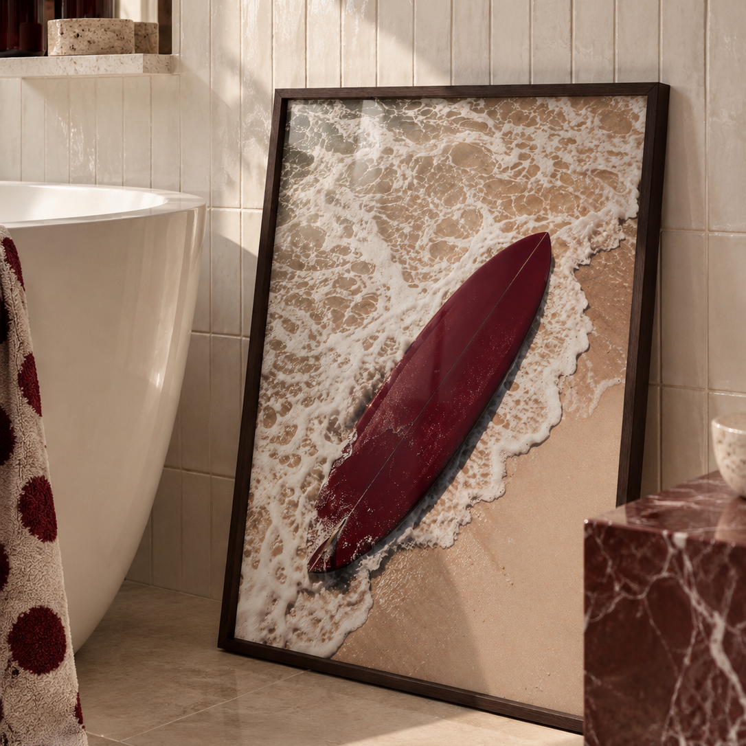 a photo of a deep red surfboard on the beach in a dark wood frame in a luxury bathroom.