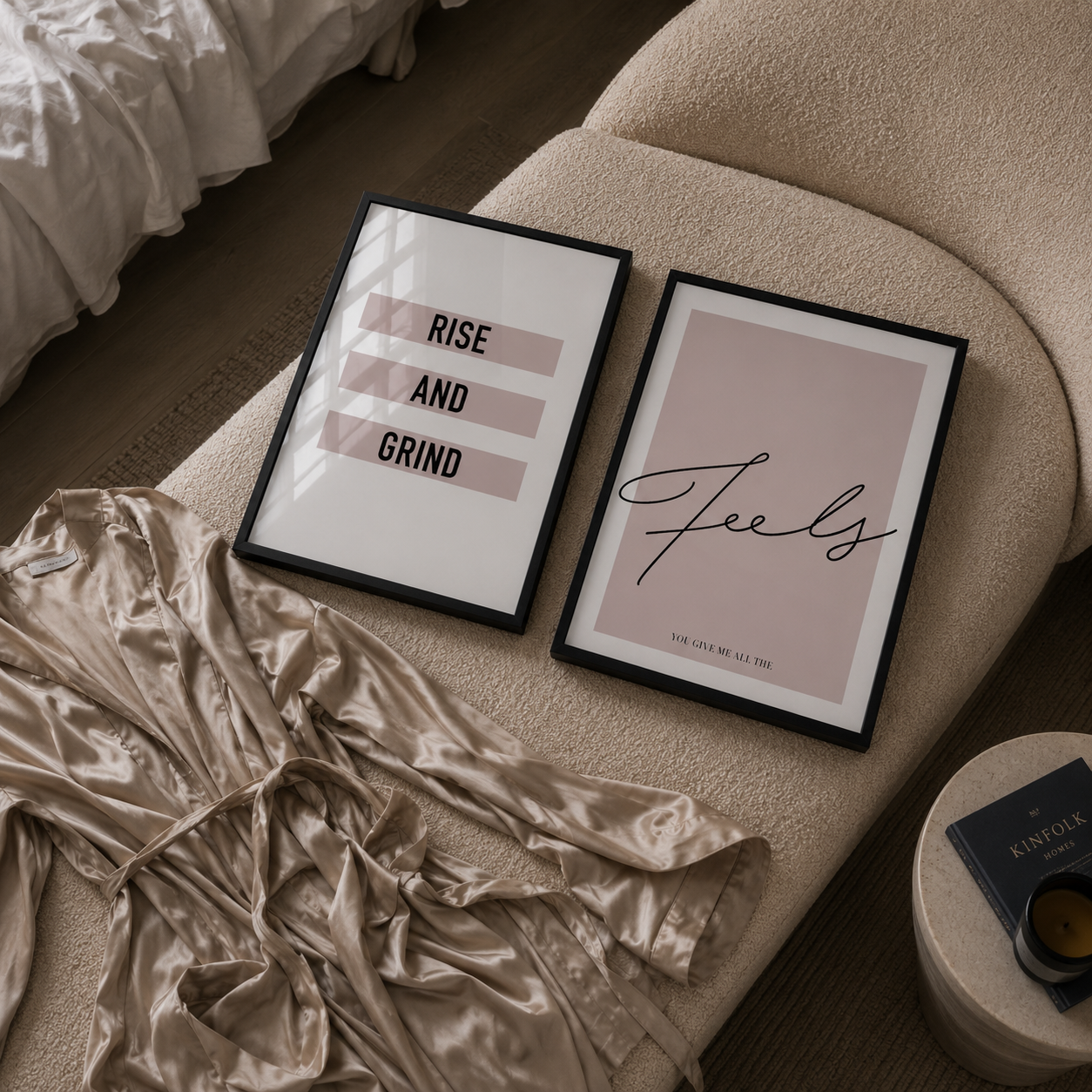 Two framed prints on a bed with 'Rise and Grind' and 'Feels' text, surrounded by crumpled bedding.